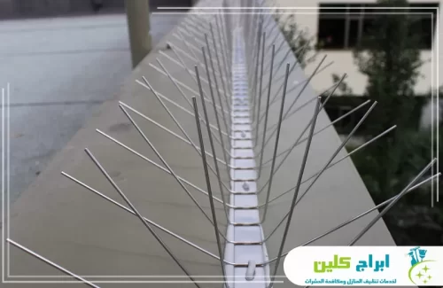 سعر تركيب طارد الحمام جدة 0550234190 ابراج كلين توضح هذه الصورة منظراً علوياً لشريط طويل من طارد الحمام المعدني المثبت على سور خرساني عريض