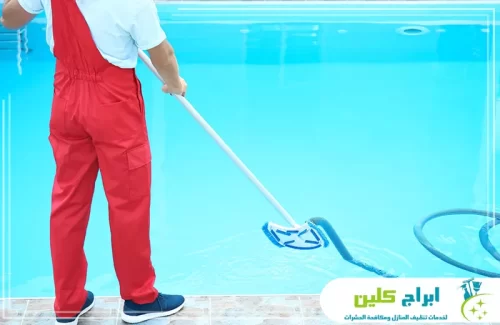 فني شركة تنظيف مسابح بصامطة يستخدم جهاز شفط أرضية المسبح لتنظيف القاع بكفاءة عالية.