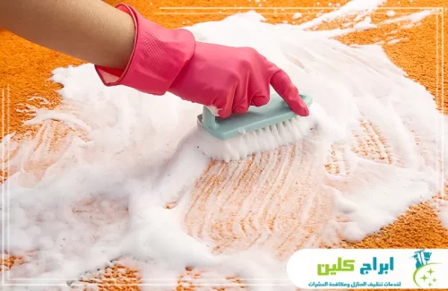 تنظيف السجاد يدويًا بفرش متخصصة مع رغوة منظفة لإزالة البقع الصعبة واستعادة لون السجاد الطبيعي