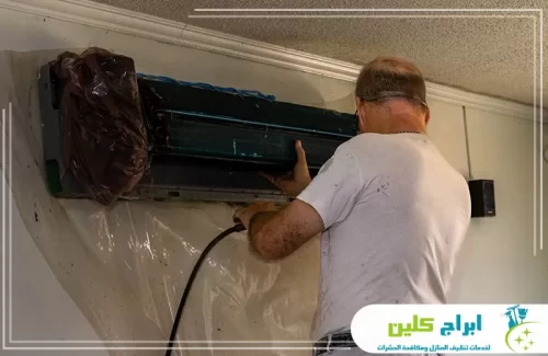 تنظيف عميق لمكيف سبليت مع حماية الجدار بغطاء خاص أثناء غسيل المكيف.