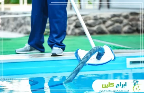 تنظيف أرضية المسبح بجهاز شفط الرواسب لإزالة الأوساخ المتراكمة في القاع.